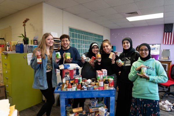 A group of six Edsel Ford students stand around a cart full of non-perishable food donated for the 2019 Battle Against Hunger food drive.