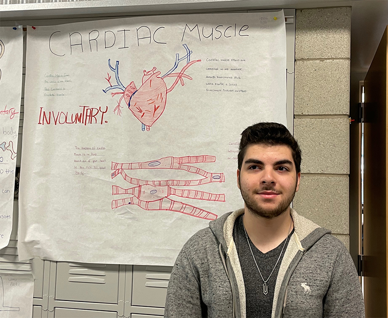 Ali Yassine stands before a poster about the cardiac muscle.