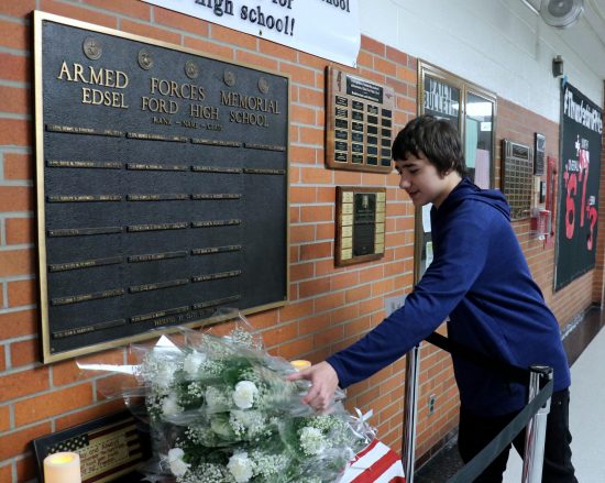 During the 2018 Memorial Day ceremony at Edsel Ford High School, a student lays flowers in front of a plaque honoring former students who died in service to our country.