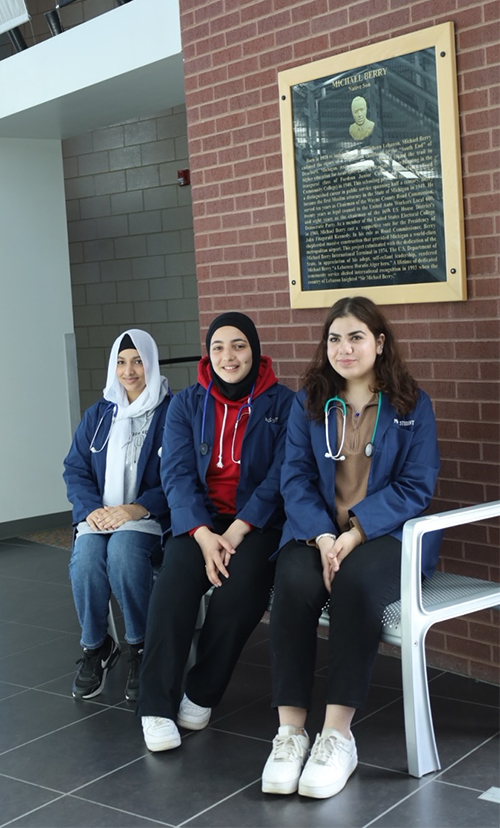 Reame Alduais, Lara Nasseredine, and Nour Mazloum pose in front of a plaque at Michael Berry Career Center.