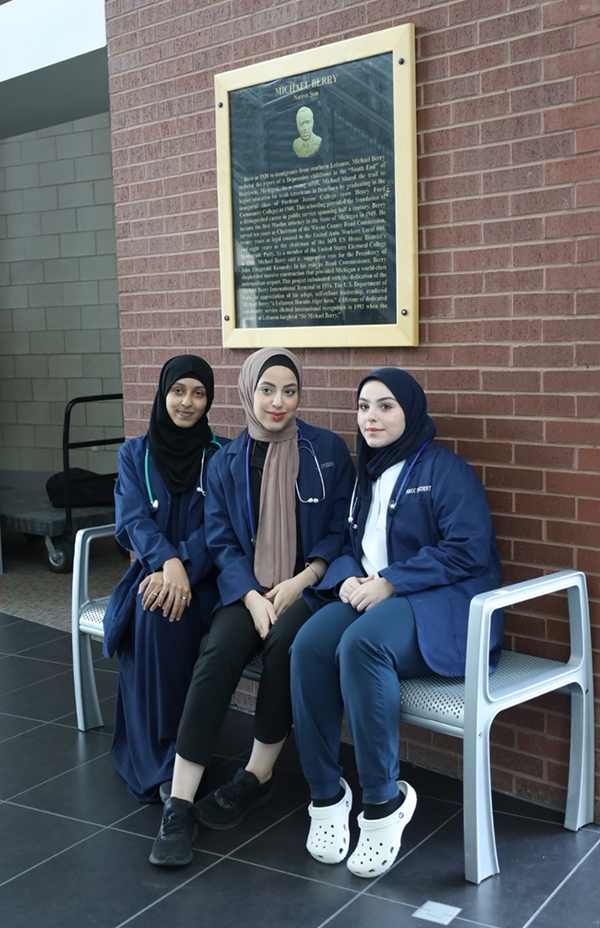 Sara Murshed, Shajan Alhilfi, and Zahraa Achi pose in front of a plaque at Michael Berry Career Center.