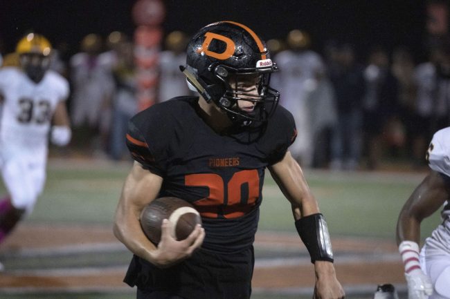 A Dearborn High football player runs with the ball during a game.