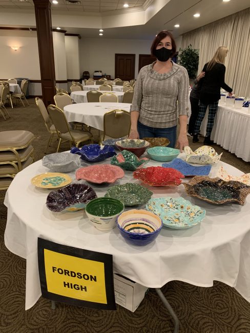 Fordson High School art teacher Leslie Curtius stands by a display of bowls made by FHS students during the 2021 Empty Bowls event.
