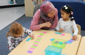 An adult works with two students at the Early Beginnings 3-year old preschool program in the fall of 2022.