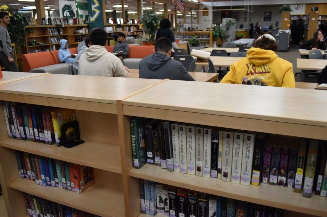 Several students sit around tables in the Dearborn High library during a class visit in October 2022.