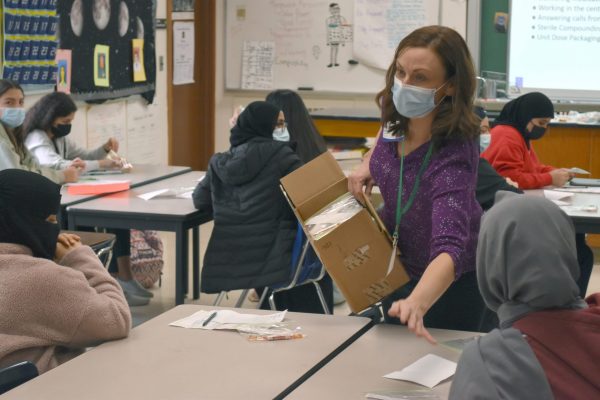 A woman hands out packets to students during a Career Day presentation at Fordson High School in 2021.