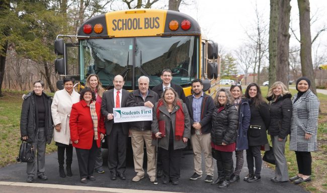 A group of elected officials and school representatives pose with the district's new electric bus on Dec. 15, 2022.