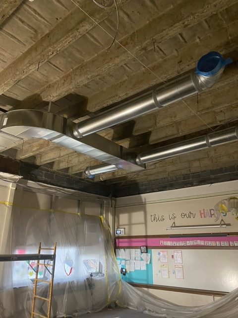 HVAC ducts are being added in the exposed ceiling of a classroom at Whitmore Bolles Elementary School.