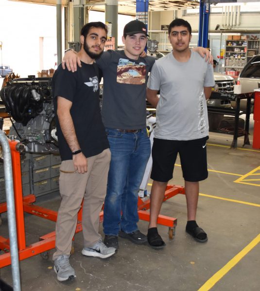 Students Salman Ahmad, Jeremy Paddock and Amir Alkhatib pose in the auto shop at Edsel Ford High School.