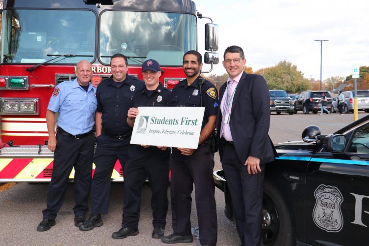 Five men, including Superintendent Glenn Maleyko pose with a Students First sign in front of a fire truck and police car.