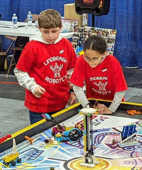 A boy and girl watch intensely as their robot attempts a task during the competition.