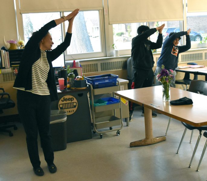 Teacher Laura Savage and two students do a standing stretch during a mindfulness lesson at Smith Middle School.