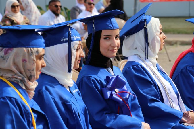 Students in graduation caps and gowns sit during the Virtual K-12 graduation ceremony