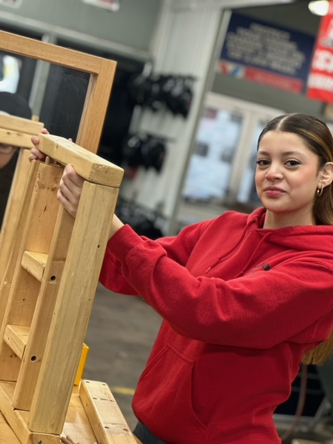 A student works on assembling a wooden frame