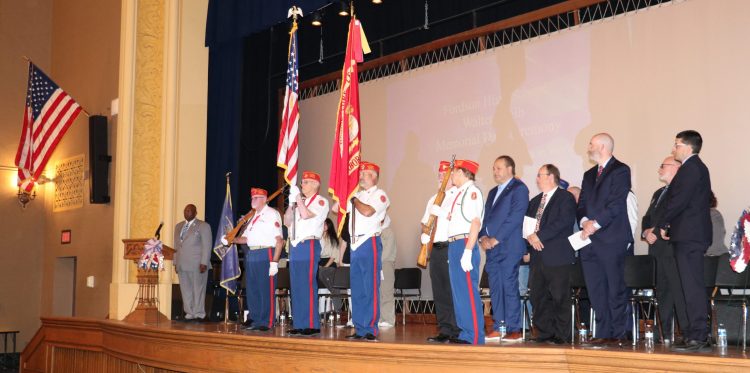 People in uniform present the U.S. flag during a Memorial Day ceremony in the Fordson High auditorium.