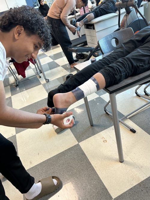 A student works on taping another student's ankle during a sports medicine class at Michael Berry Career Center