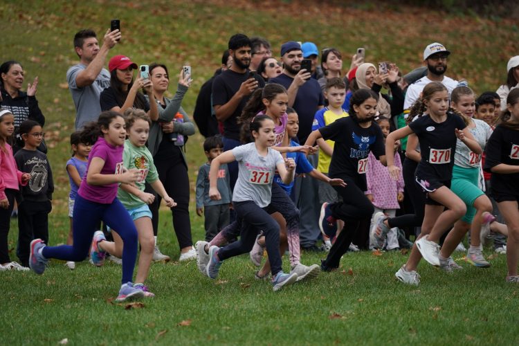 A group of girls start the Cipriano Cross Country race while a line of parents look on