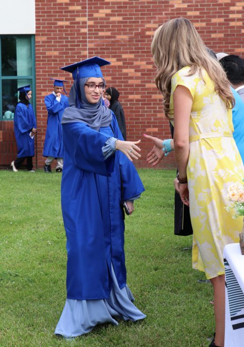 A graduating student reaches to shake hands with an official