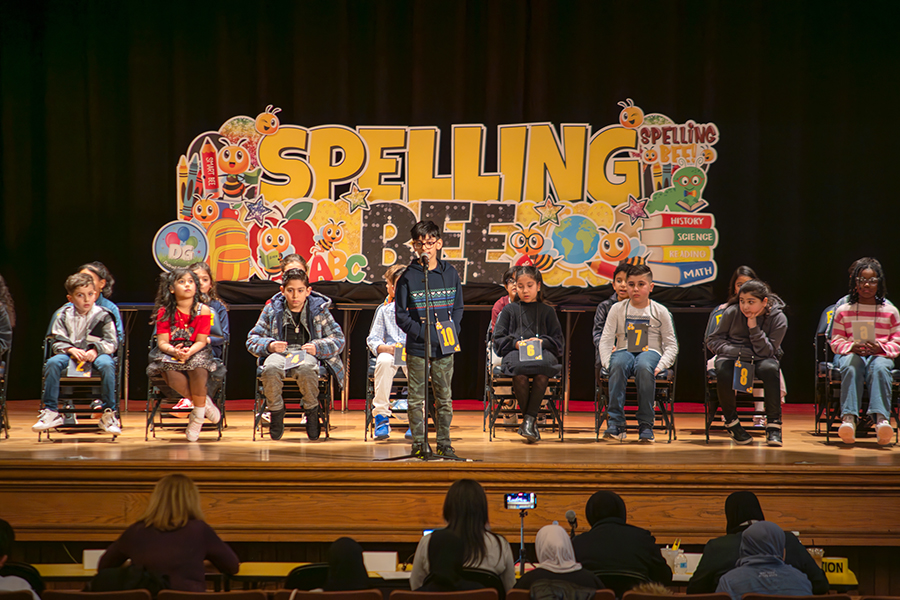 A student stands before a microphone during the District Wide Spelling Bee.