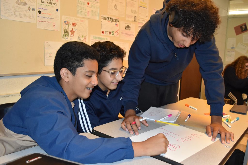 Three Edsel Ford students work on a poster that says Words Hurt.