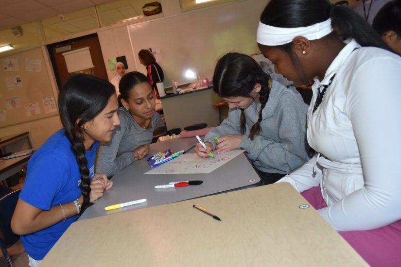 Four students work on a poster during class at Edsel Ford High.