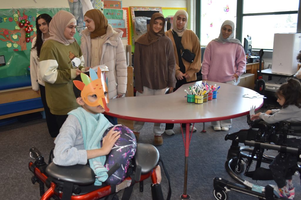 Volunteers with the Creative Needs Project stand in a classroom.