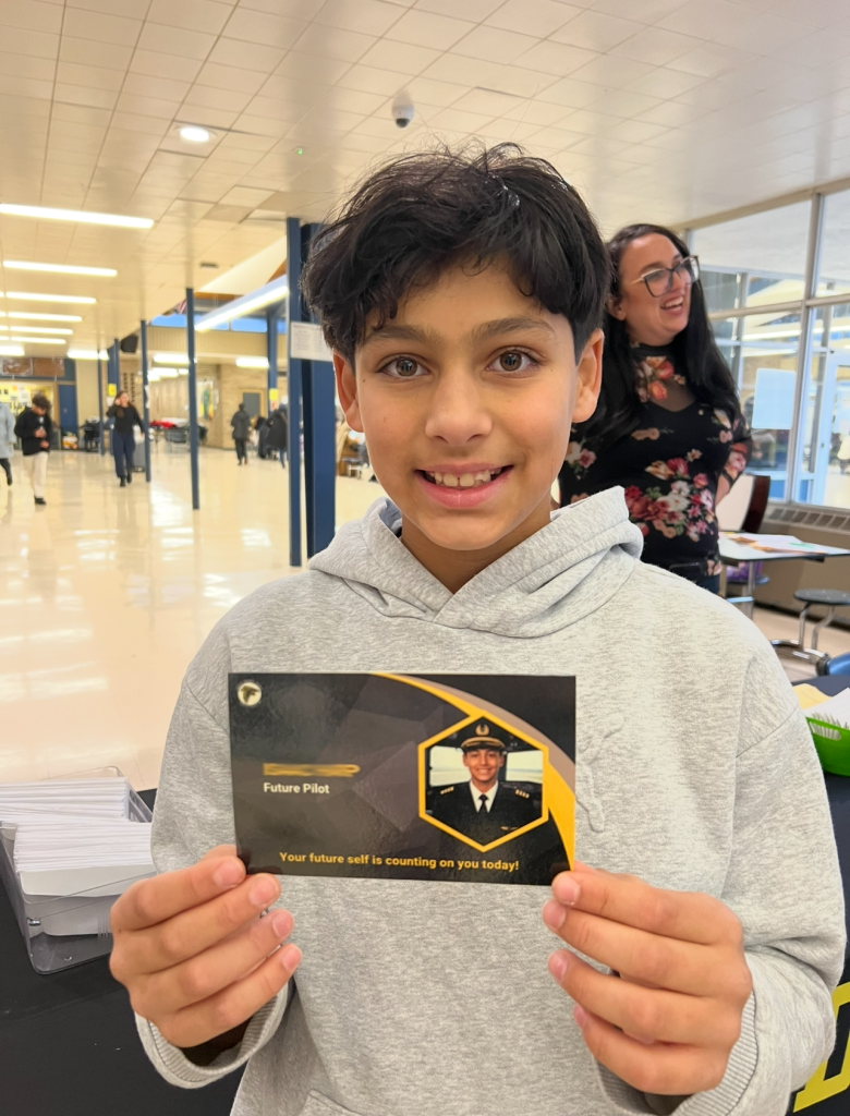 A student shows a card with a picture of him as a future pilot