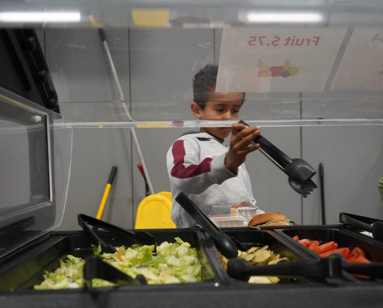 Scooping veggies A student picks items from a veggie and fruit bar.