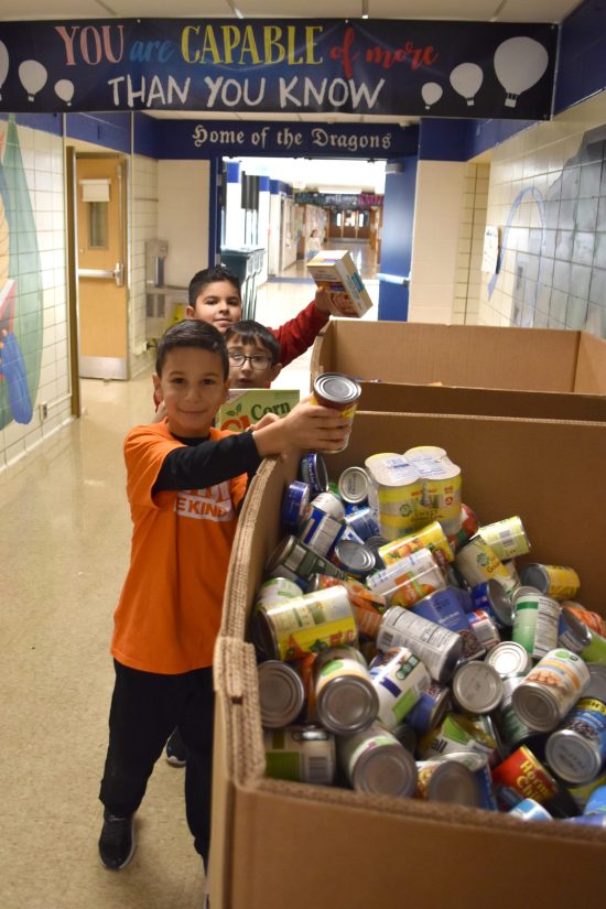 Howard Elementary students put donated food into large cardboard boxes.