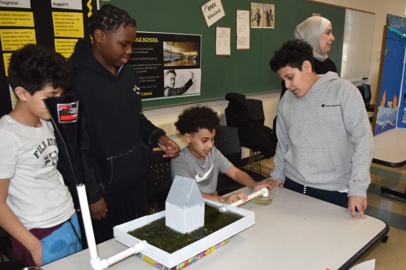 Boys runoff Stout students use a model house and lawn to show how grass slows stormwater runoff.