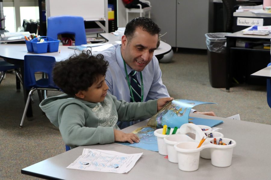 Mike Esseily looks at a book with a young student