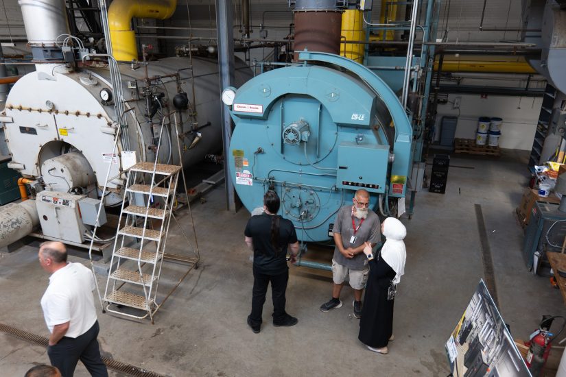 People stand next to large, old boilers at Lowrey School in August 2026